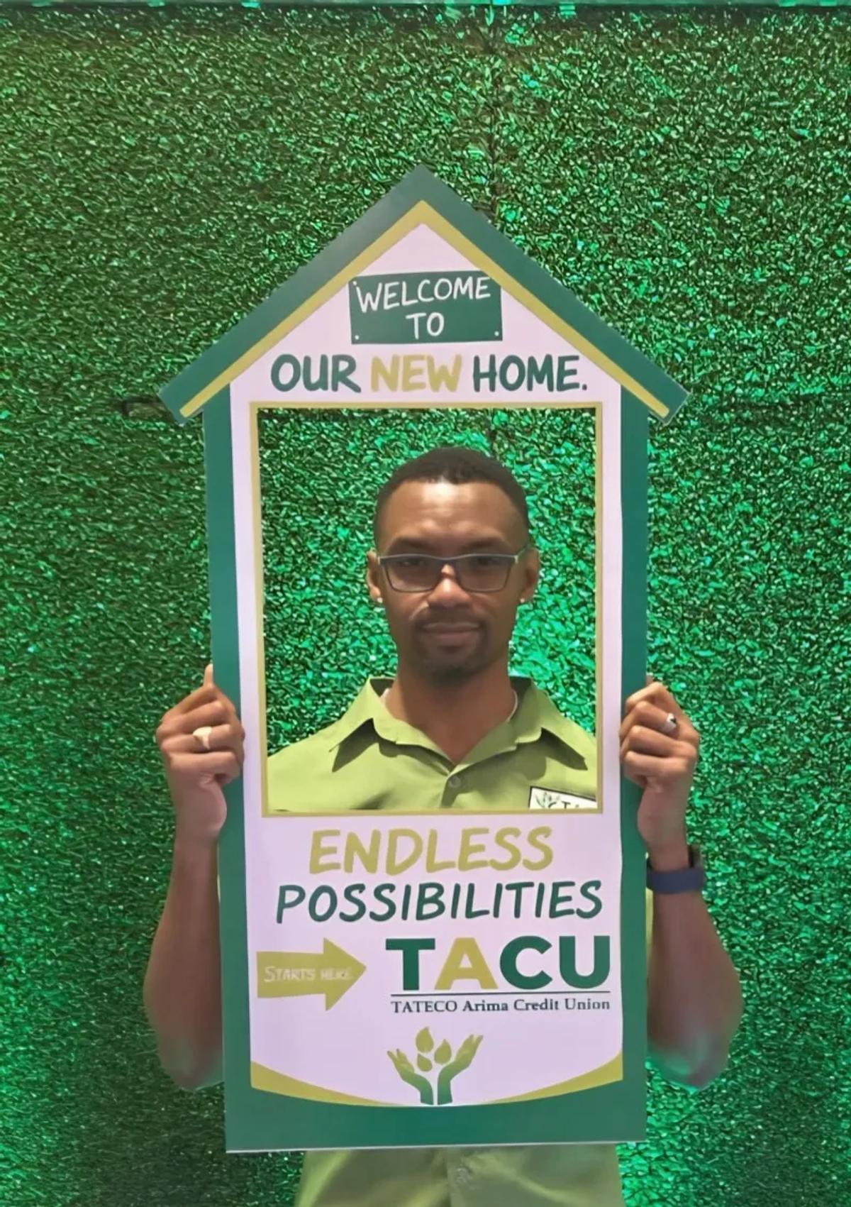 Member posing with TACU photo frame prop reading Welcome to Our New Home at the 72nd AGM