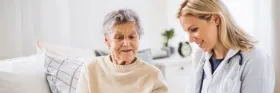 Senior and caregiver coversating on the couch