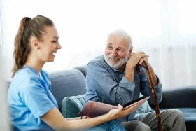 Caregiver reading and laughing with dementia care patient.