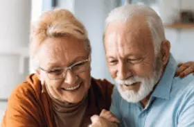 Elderly couple smile as they review documents together