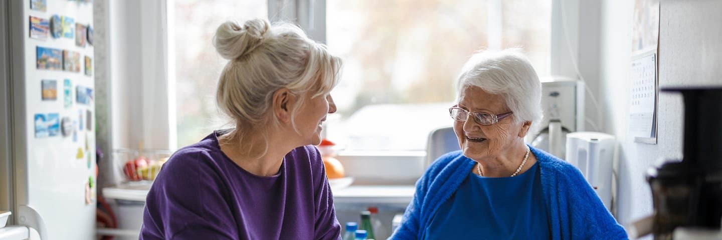 Senior sitting at table with daughter in the kitchen