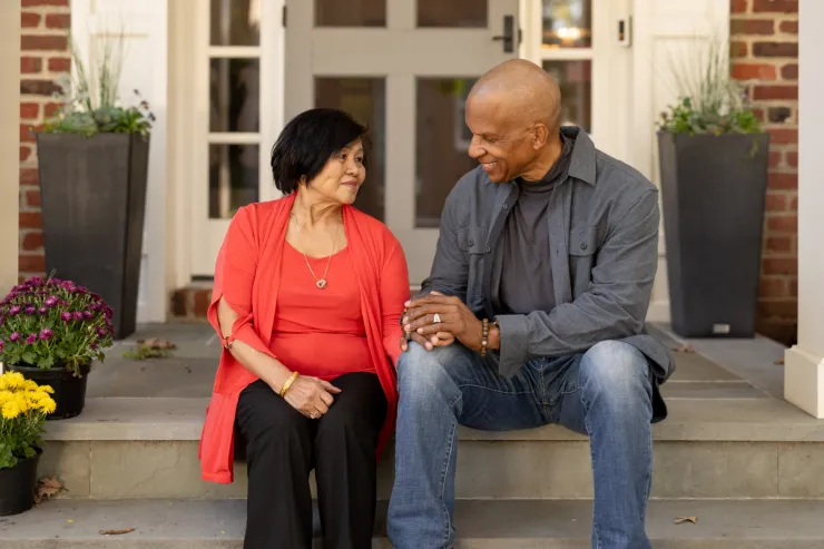 Older adult sits with a family member outside a home, representing the process of exploring senior care options together.
