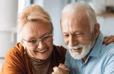 Elderly couple smile as they review documents together
