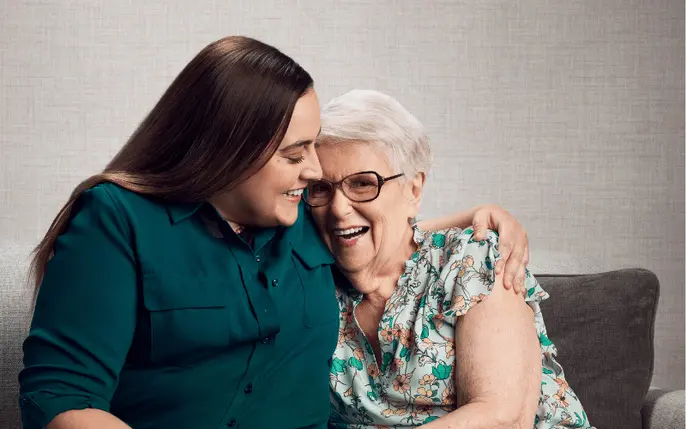 Adult daughter talks with her older mother outside a home, representing the importance of early conversations about senior care.