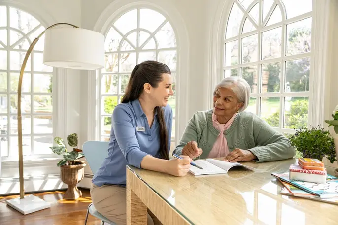 Professional caregiver and an older woman enjoy a tabletop activity together, illustrating the companionship, engagement, and trust that help home care succeed.