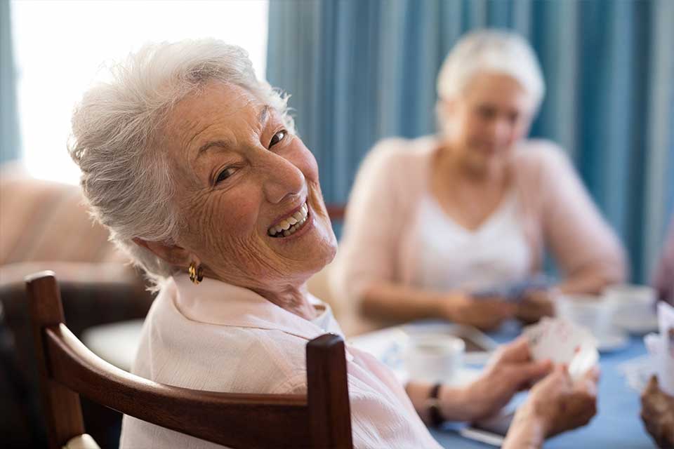 Elderly women playing cards in a senior living facility.