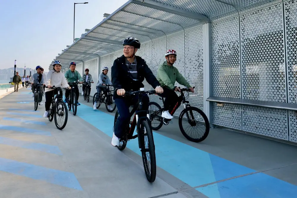 people cycling waterfront boardwalk harbour view Hong Kong