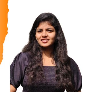 A portrait photo of Deeksha, a young woman with long wavy dark hair, wearing a dark top, smiling at the camera.