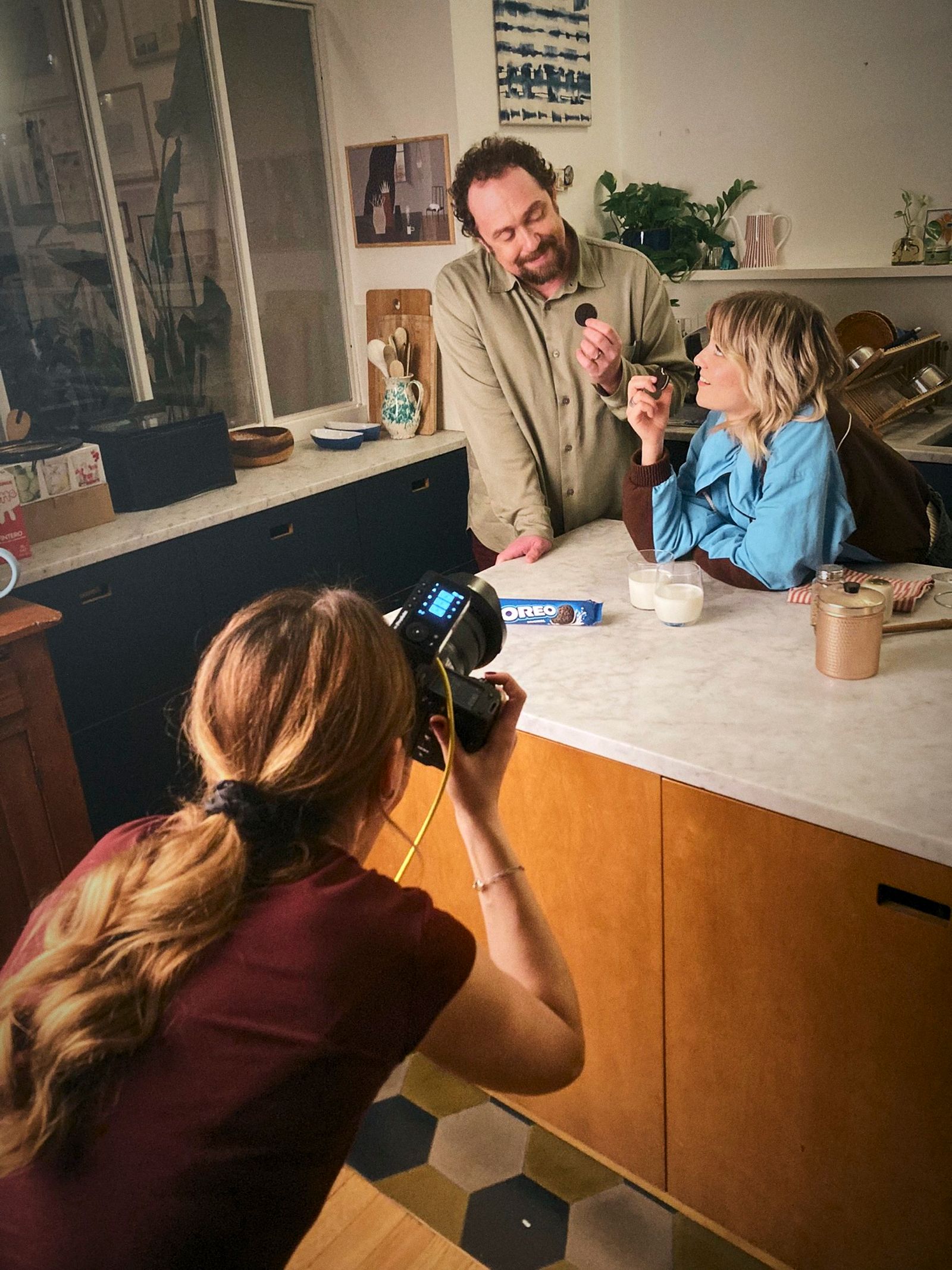 Lizzie Mayson crouched with a camera photographing a couple at a marble kitchen counter on the Oreo shoot in Milano.