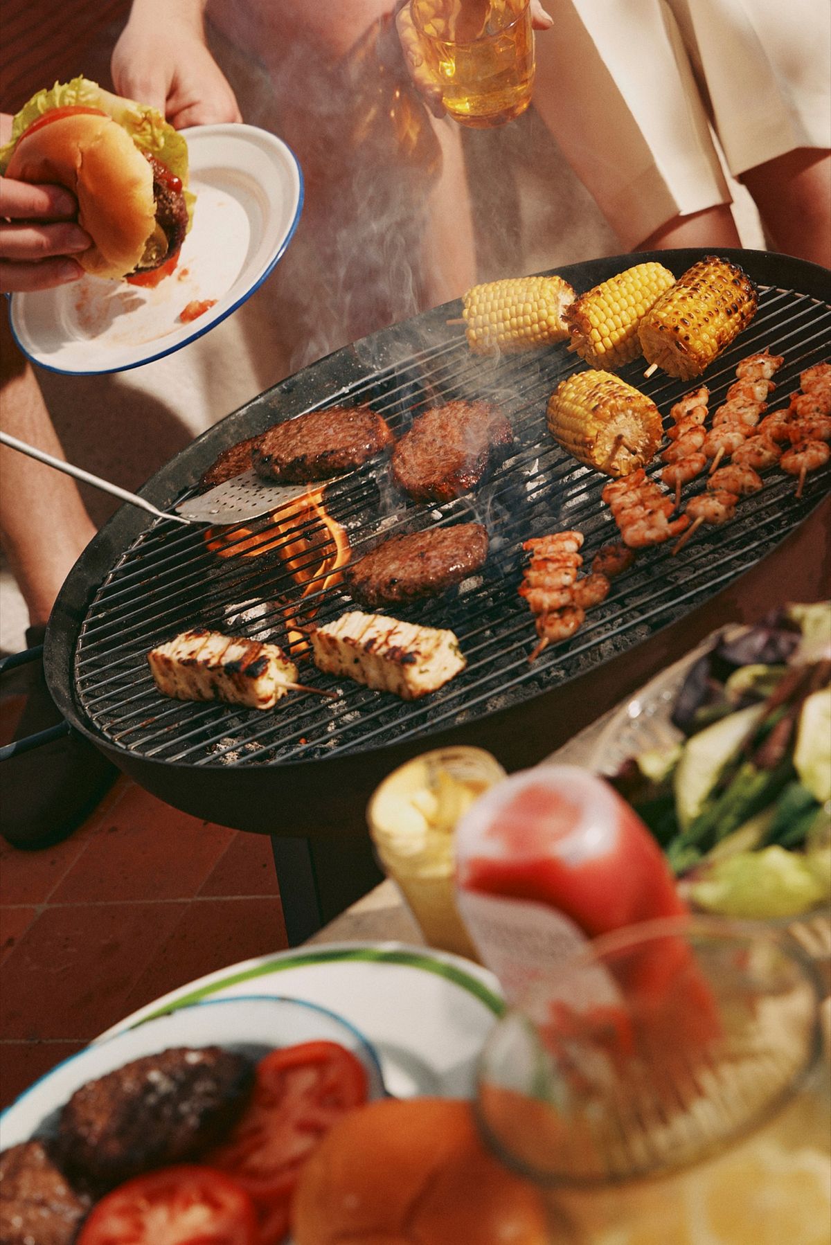 Charcoal barbecue loaded with burgers, corn, prawn and halloumi skewers on the Waitrose summer shoot.