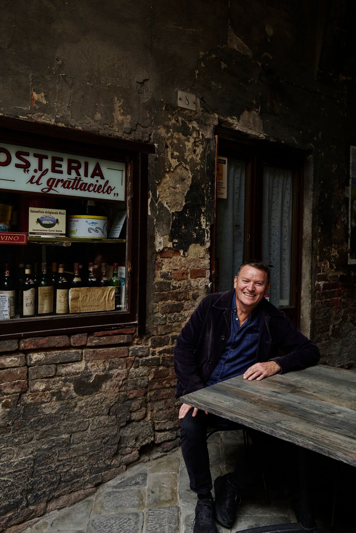 Theo Randall walking down a Tuscan street with market shopping, behind the scenes of The Italian Table.