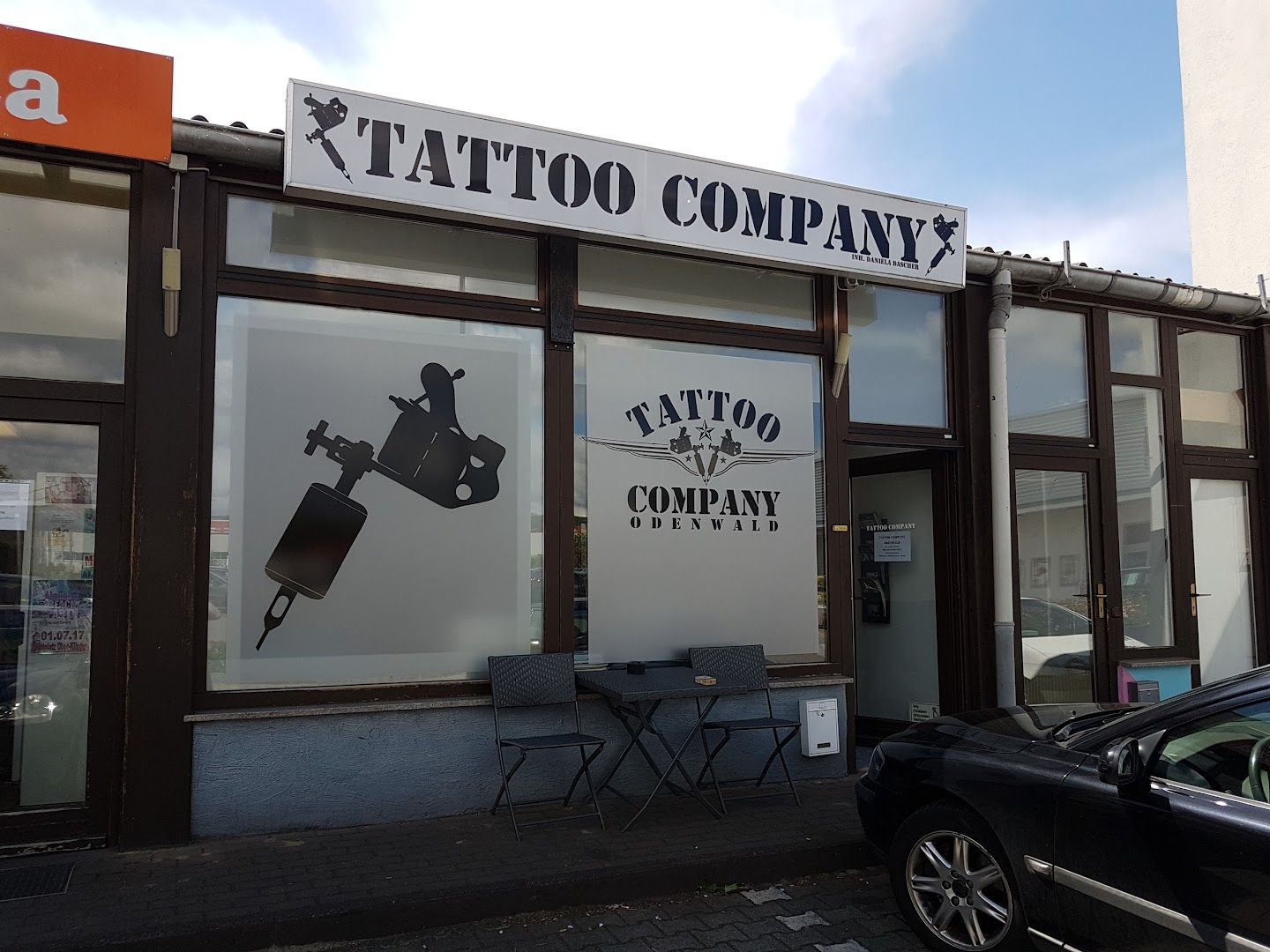 a black car parked in front of a cover-up tattoo shop, odenwaldkreis, germany