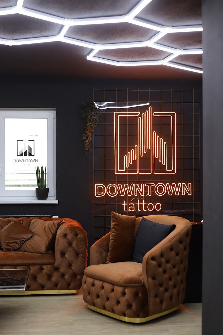 a living room with two brown couches and a neon sign