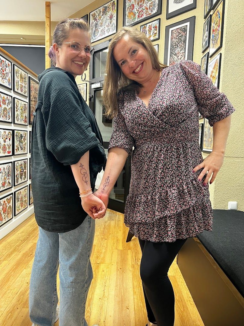 two people standing in front of a wall with pictures on it