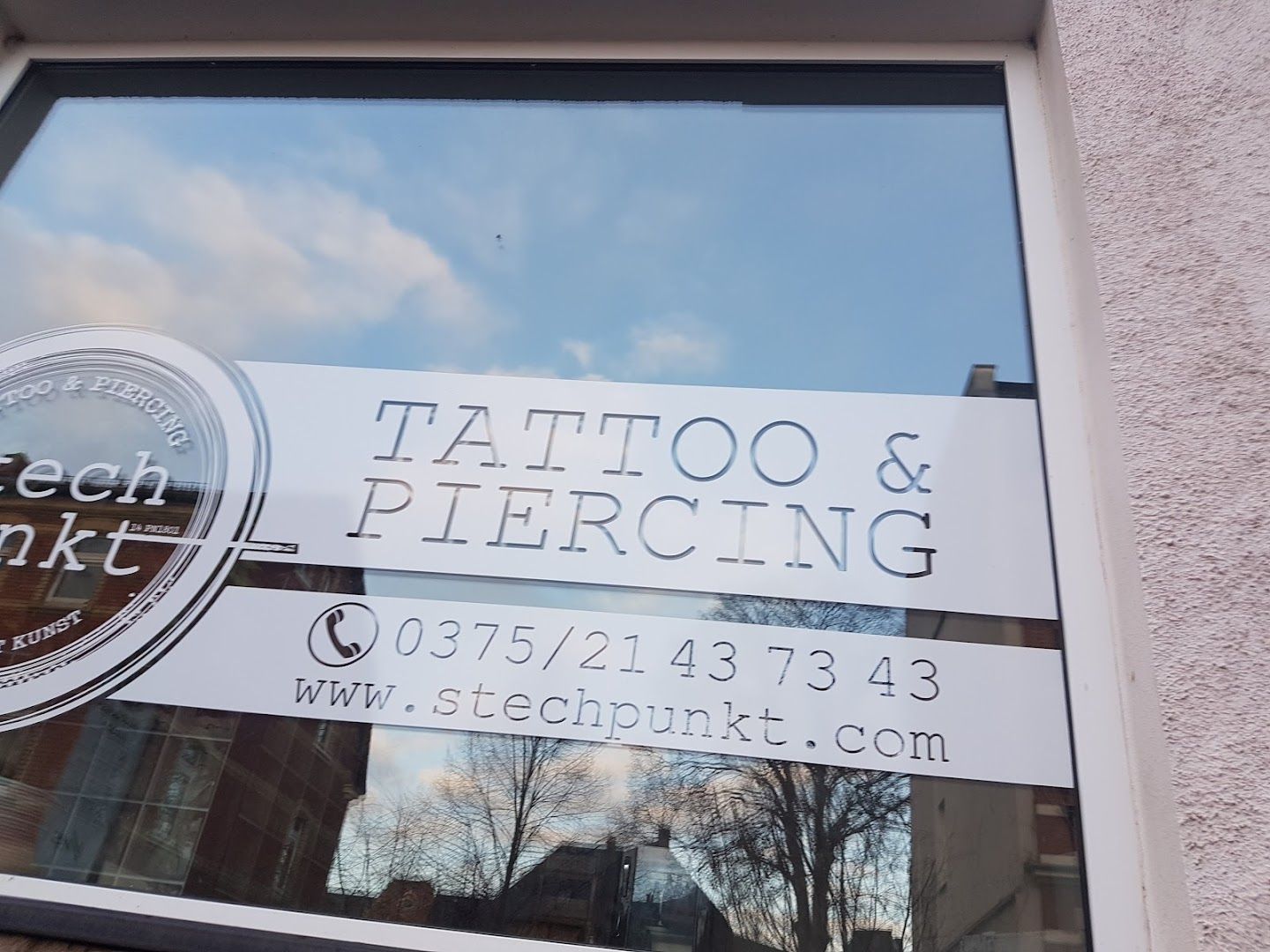 a window with a sign that says narben tattoo and piercing, zwickau, germany