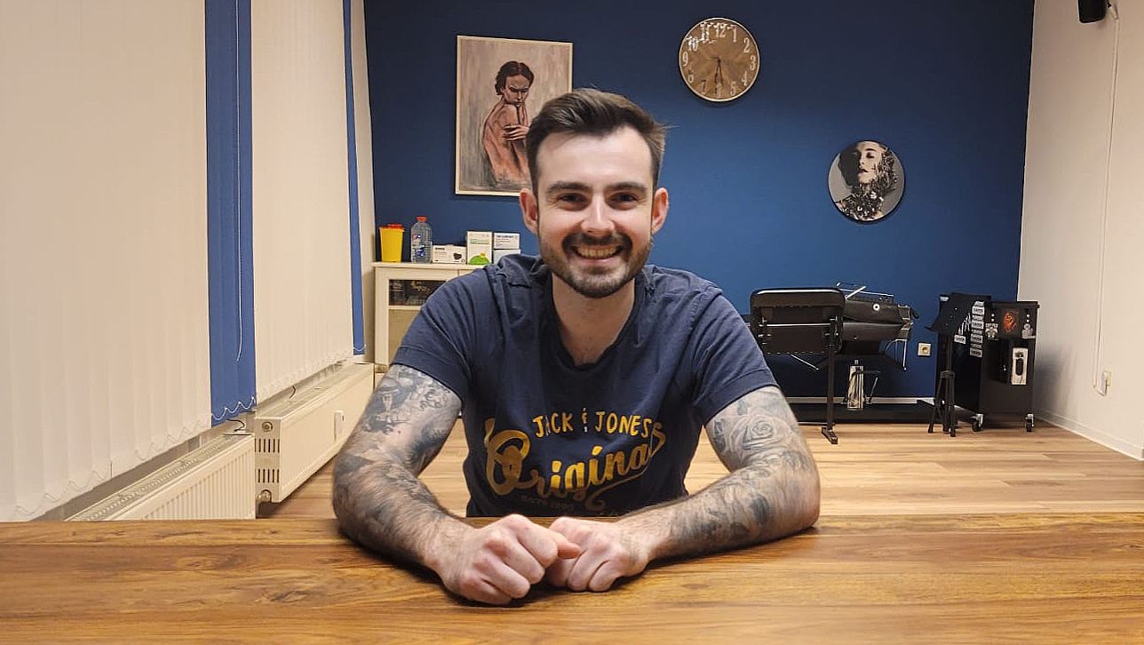 a man sitting at a table with a narben tattoo on his arm, amberg-sulzbach, germany