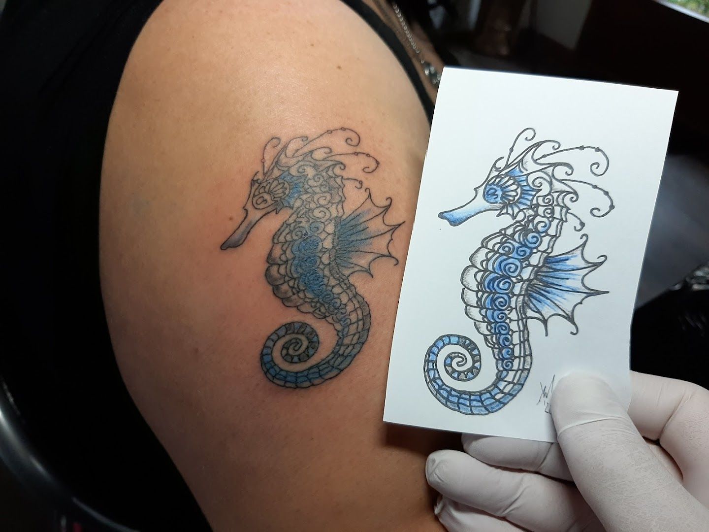 a narben tattoo artist holding a piece of paper with a seahorse on it, märkischer kreis, germany