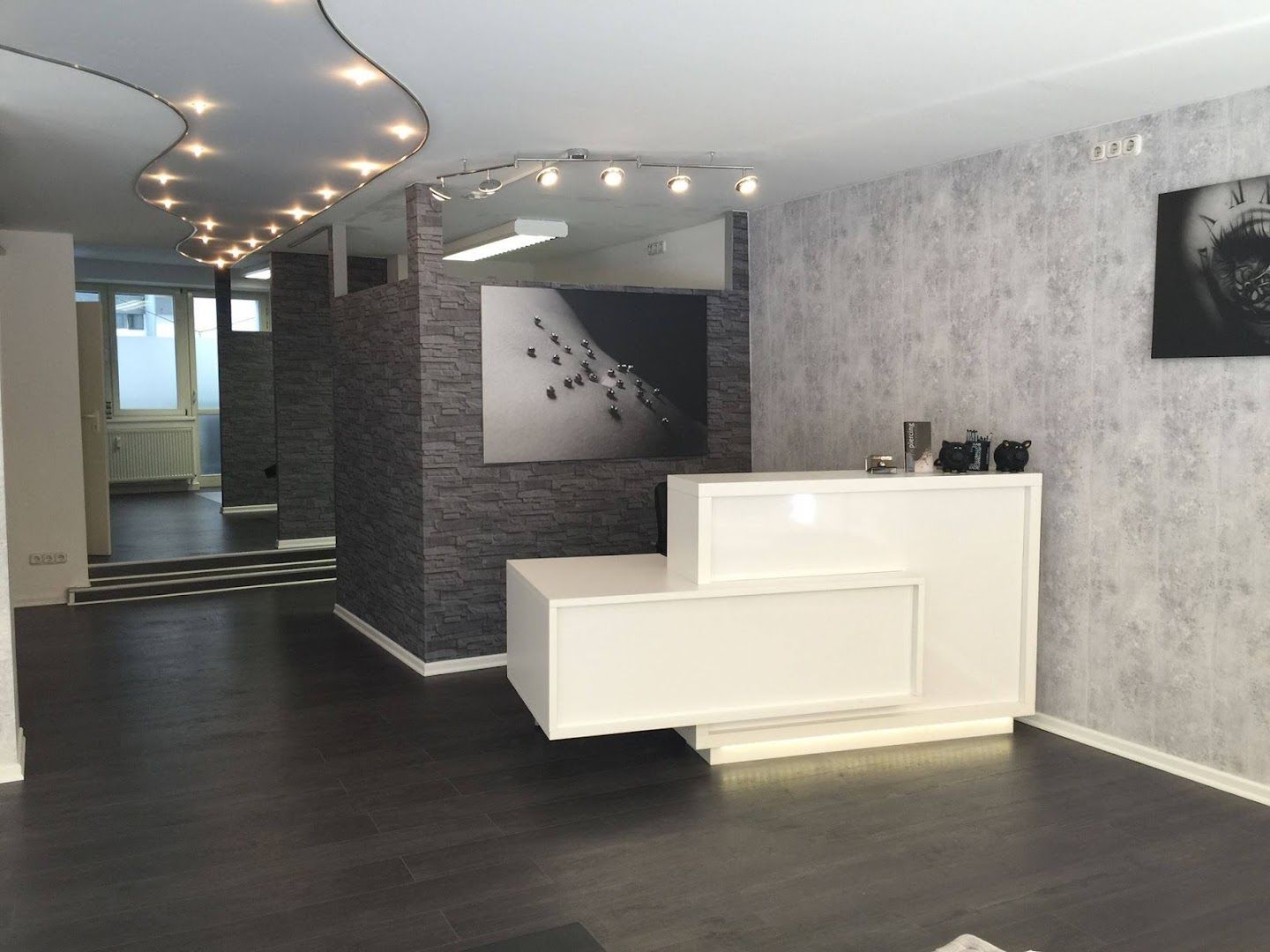 a reception area with a white reception desk and a black and white wallpaper