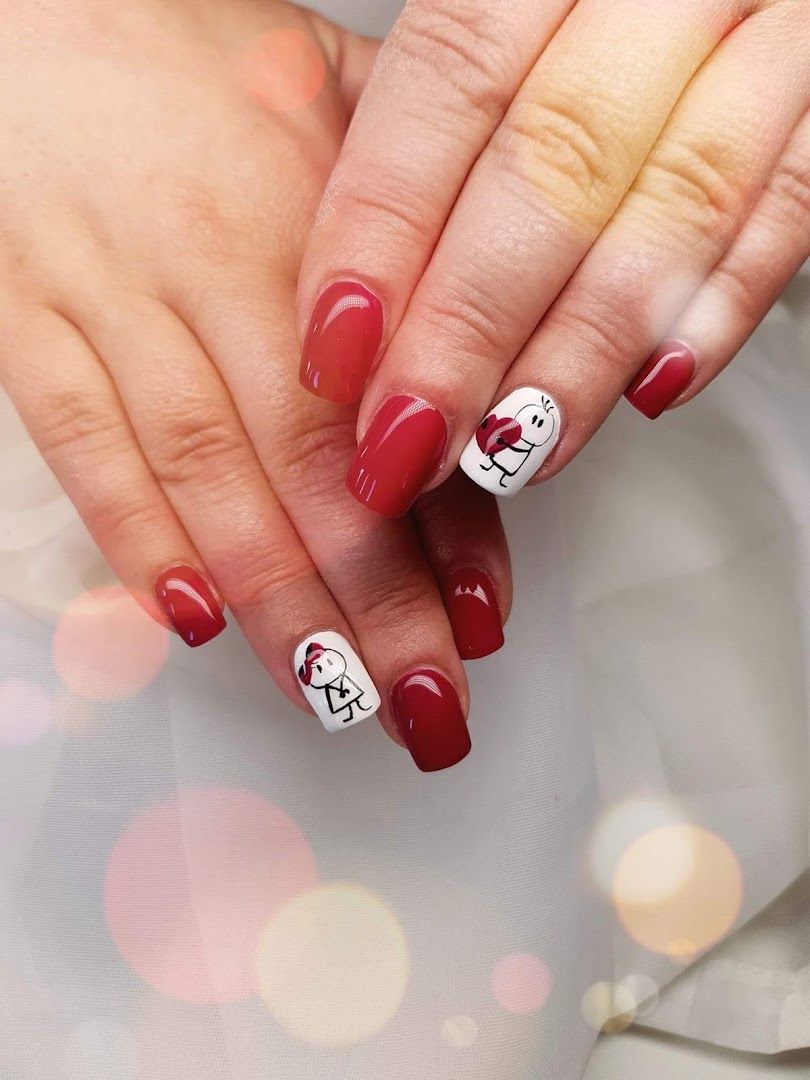 a woman's hands with red and white nails with a smiley face on it