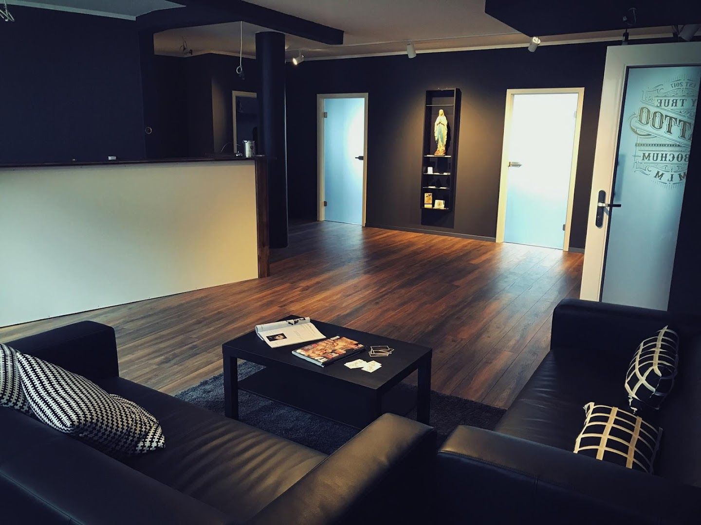 a living room with black furniture and a wooden floor