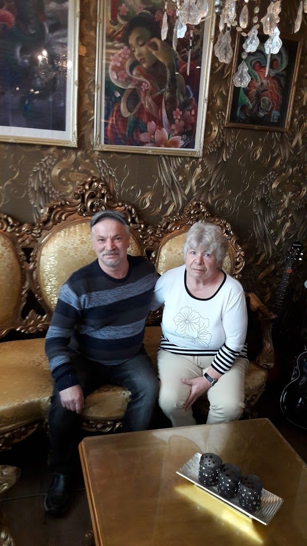 a man and woman sitting in a room with gold furniture