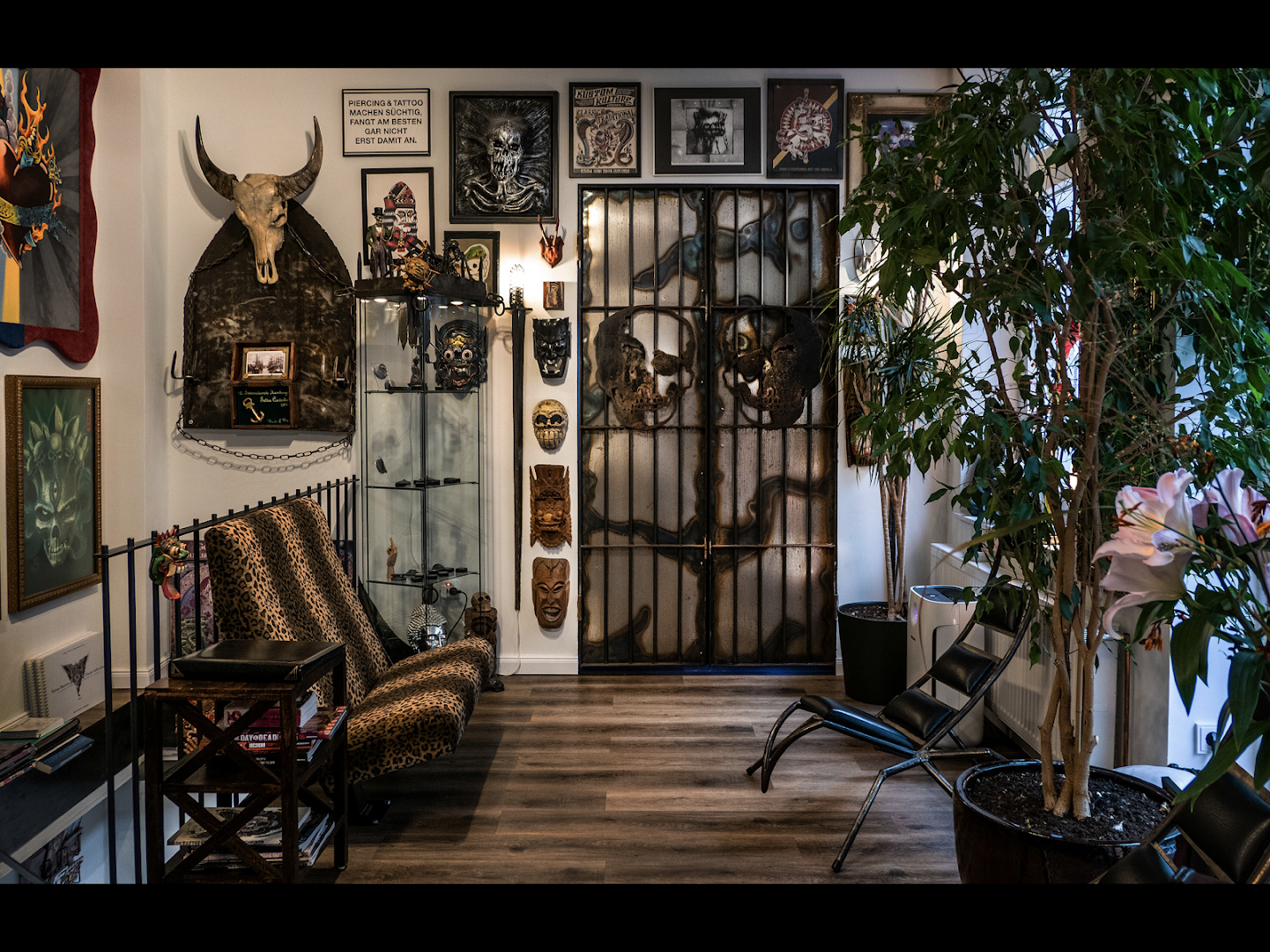 a room with a chair, a plant, and a wall with pictures