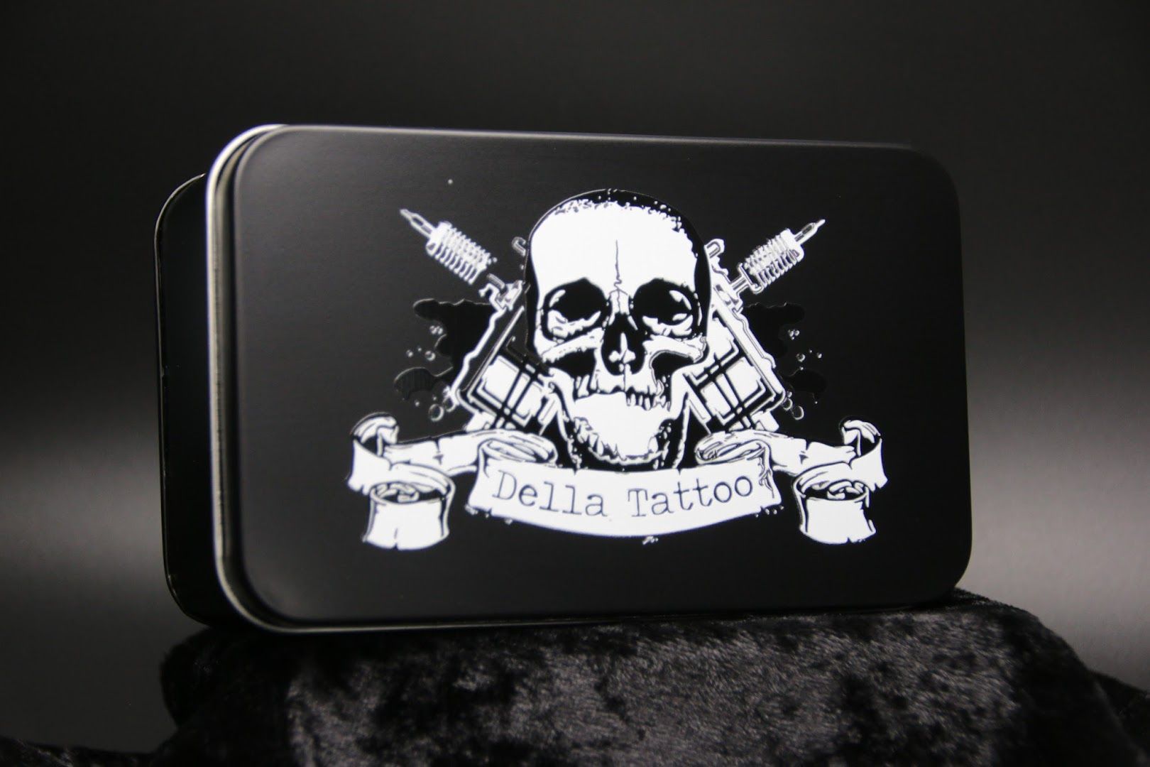 a black and white tin with a skull and guns