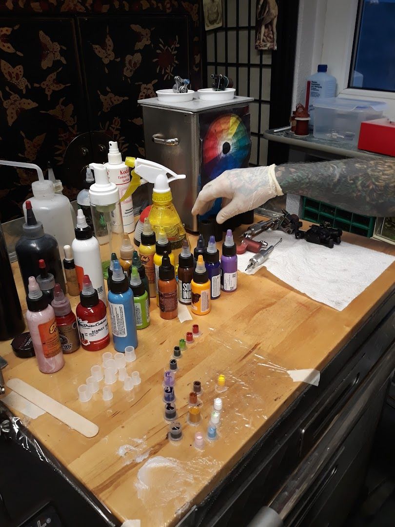 a table with a bunch of paint and a bottle of paint