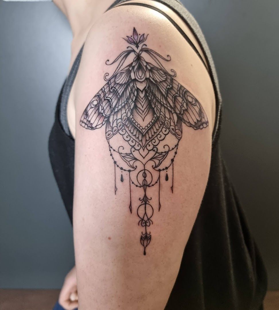 a woman's shoulder with a trashpolka tattoos of a moth, bayreuth, germany