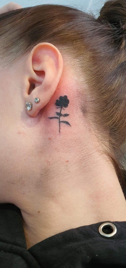 a woman with a small black flower narben tattoo on her ear, friesland, germany