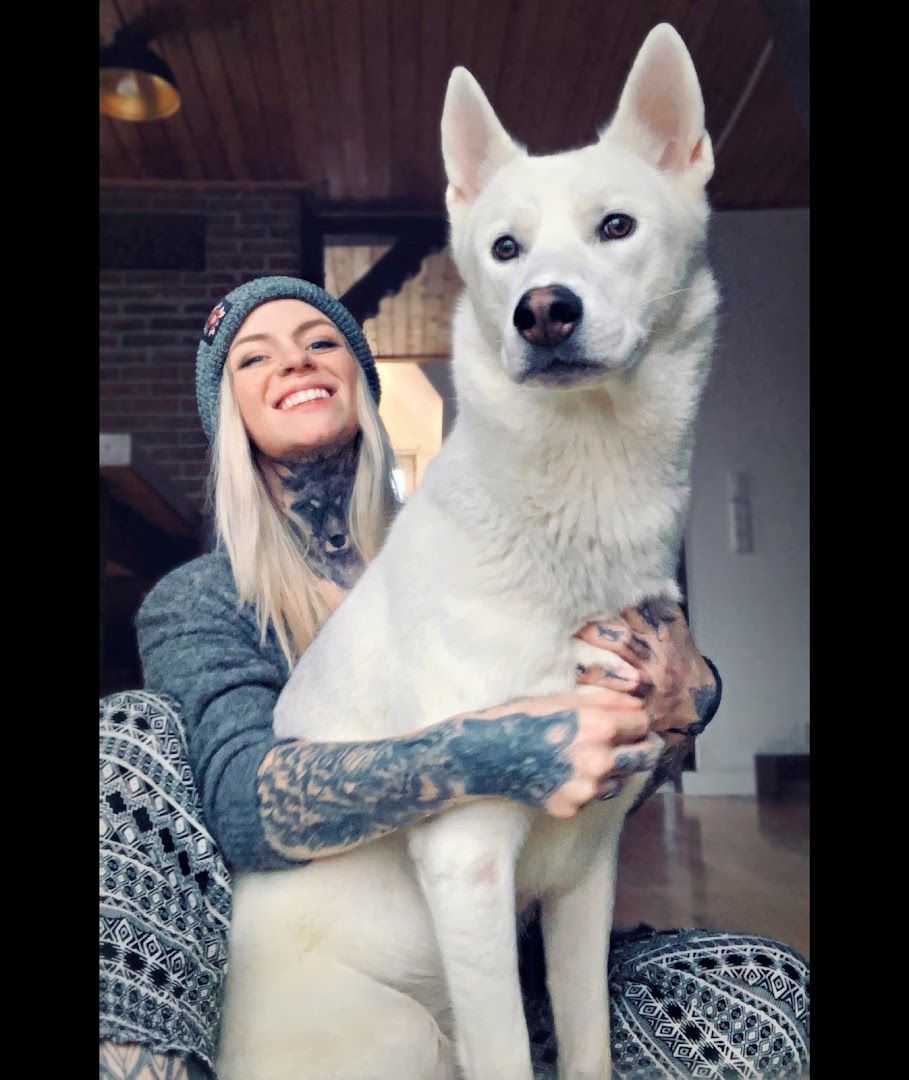 a woman holding a white dog in her arms