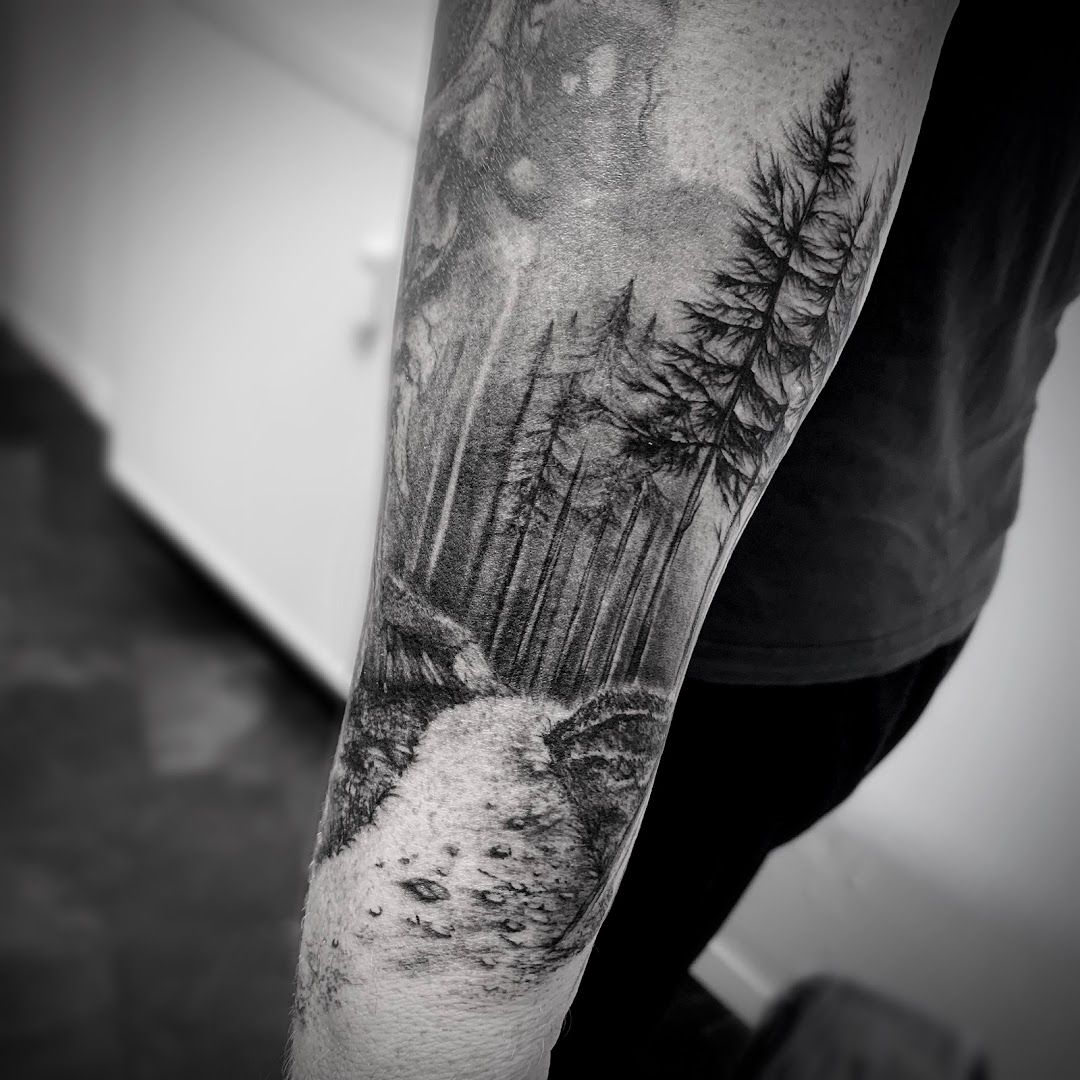 a man's forearm with a forest scene on it