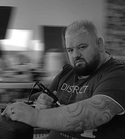 a man with a beard and narben tattoos sitting on a bench, frankfurt, germany