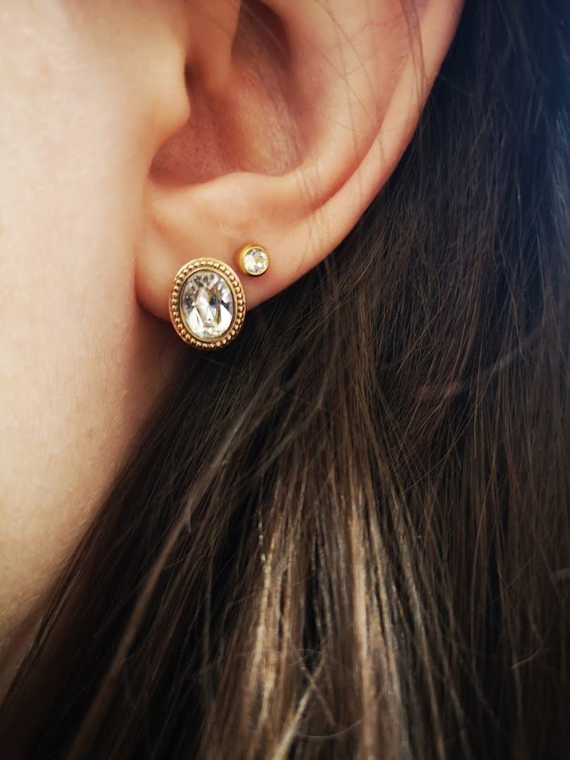 a woman wearing a gold earring with a white stone