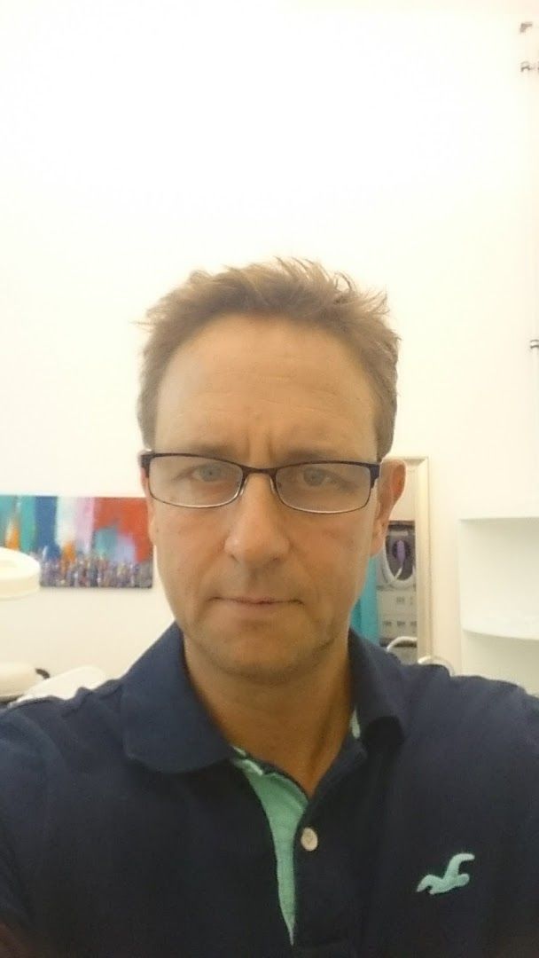 a man wearing glasses and a polo shirt