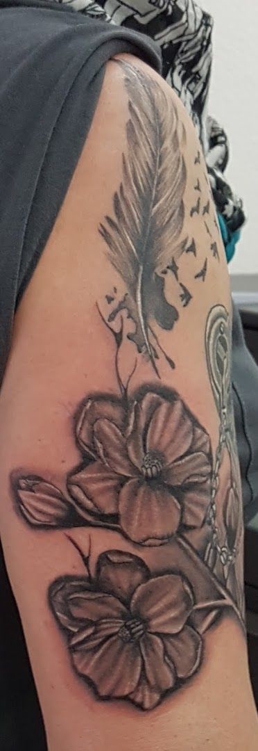 a blackwork tattoo with flowers and a feather on it, konstanz, germany