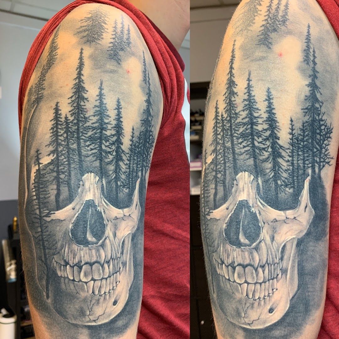 a skull with trees and pine trees on the back of the arm