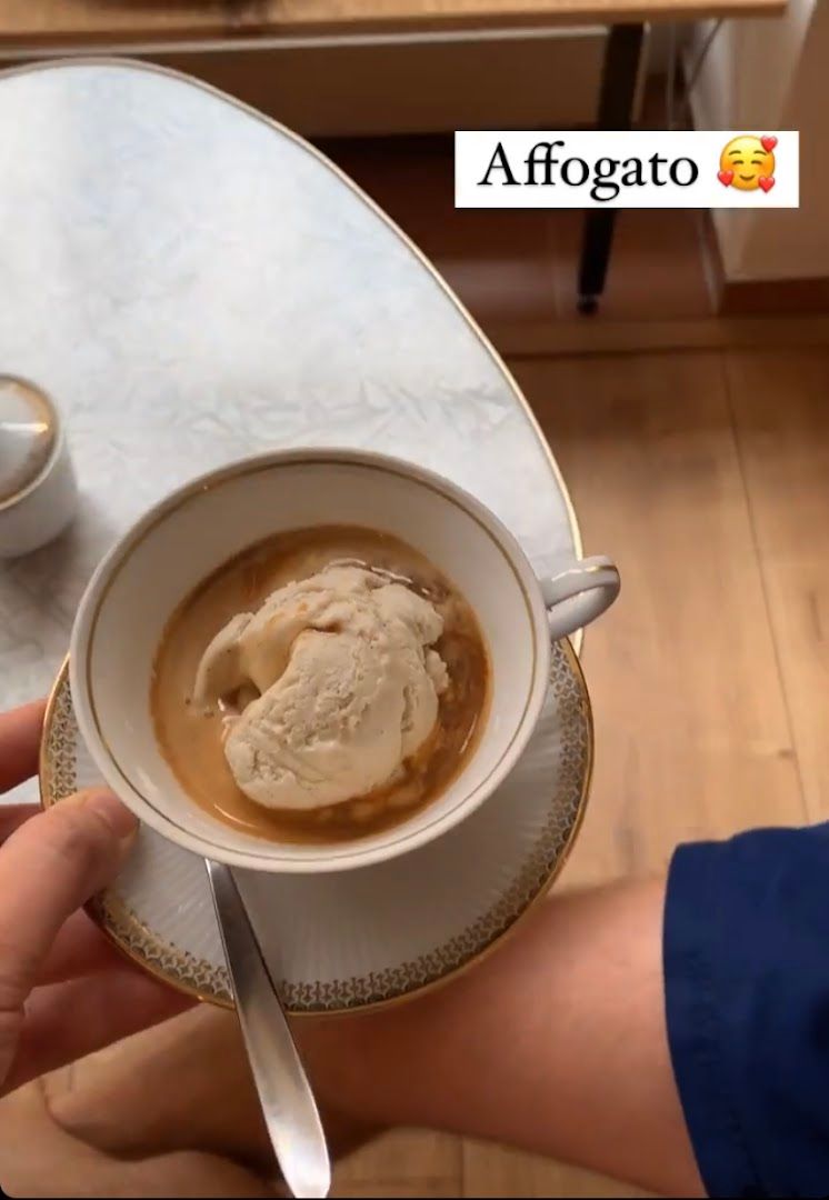 a person holding a cup of coffee with ice cream