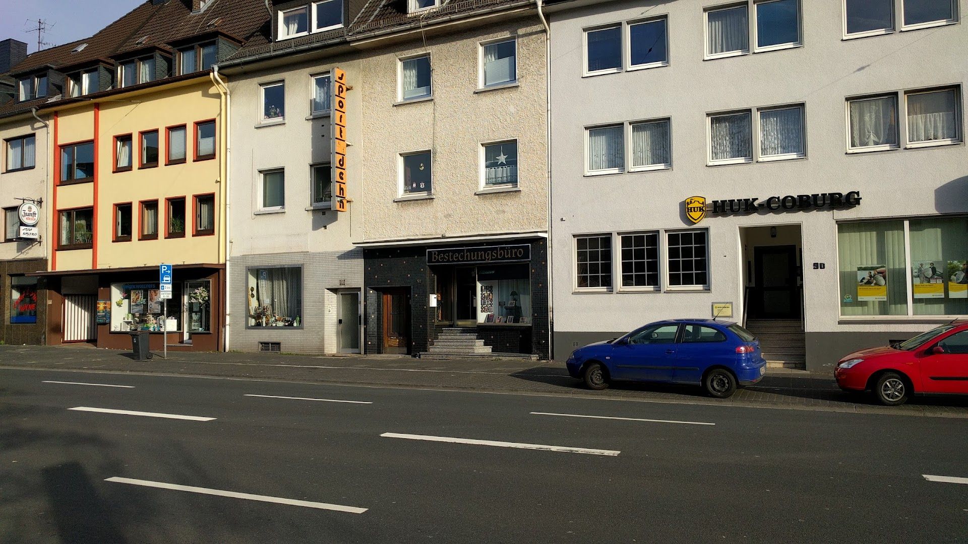 a street with a row of buildings and a car parked in front