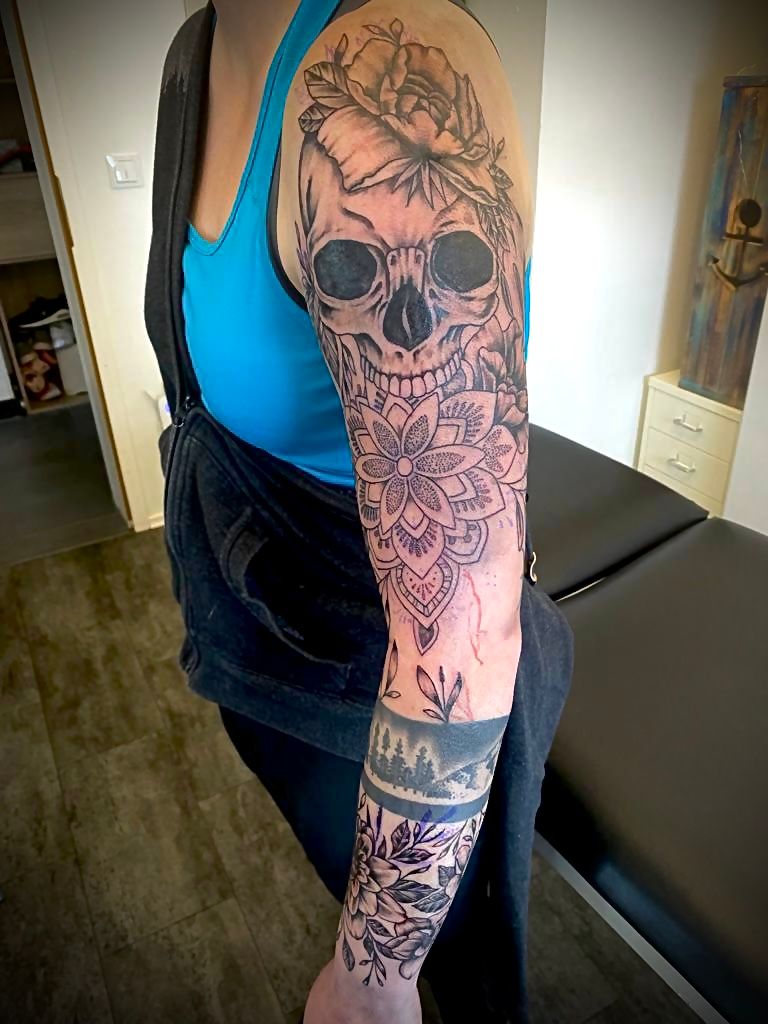 a woman with a skull and flowers on her arm