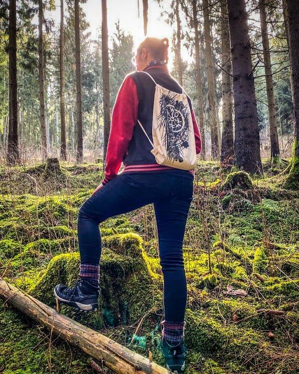 a woman sitting on a log in the woods