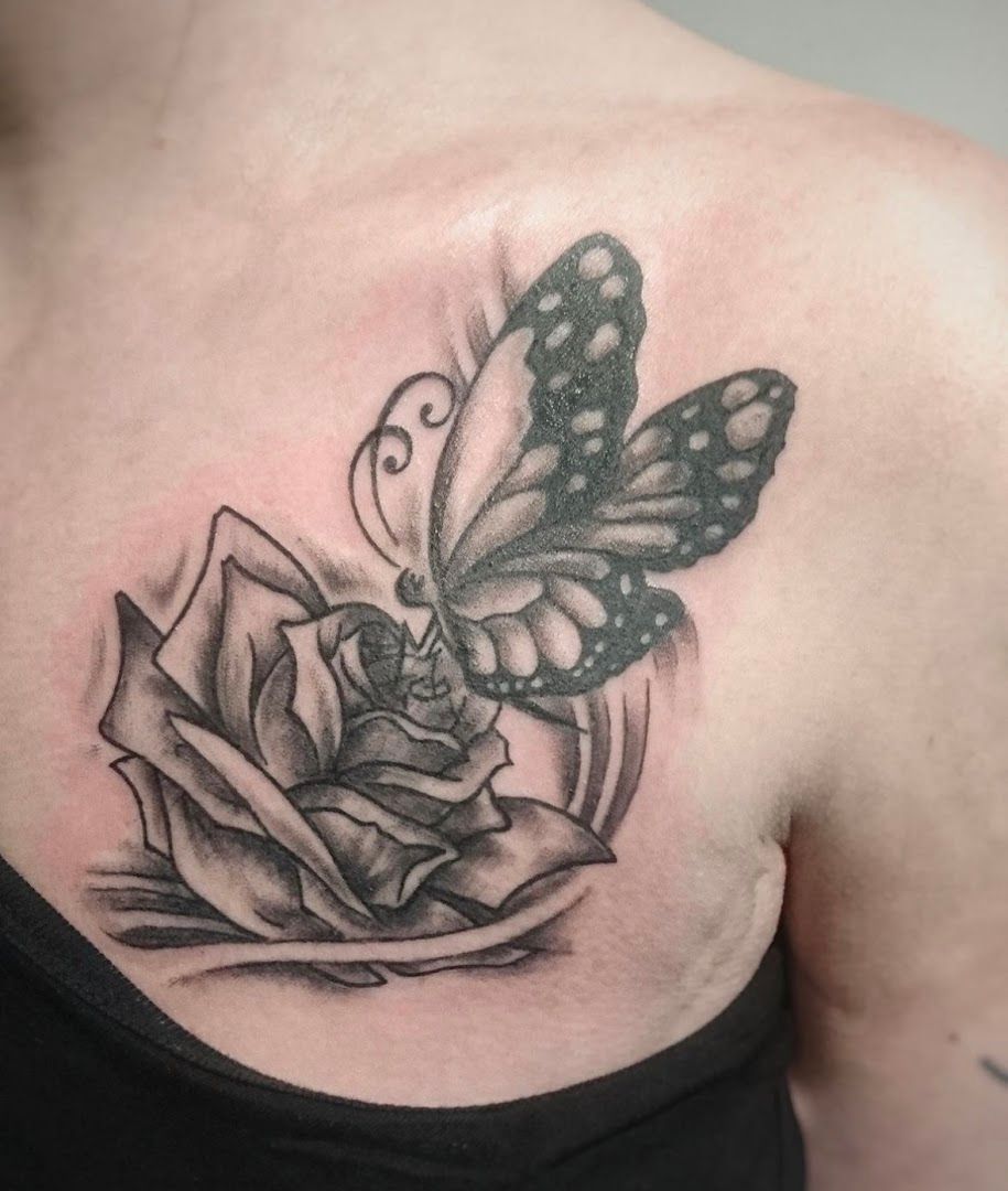 a black and white cover-up tattoo of a butterfly on a rose, berlin, germany