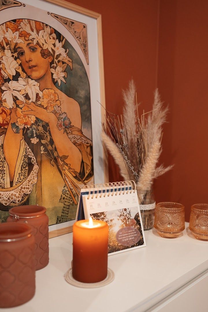 a candle, a painting and a vase on a shelf