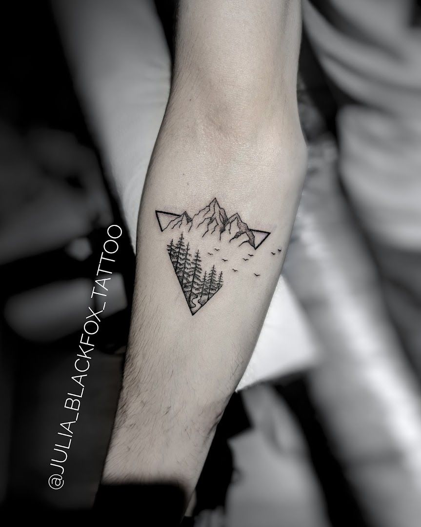 a man's forearm narben tattoo with a mountain and pine trees, frankfurt, germany