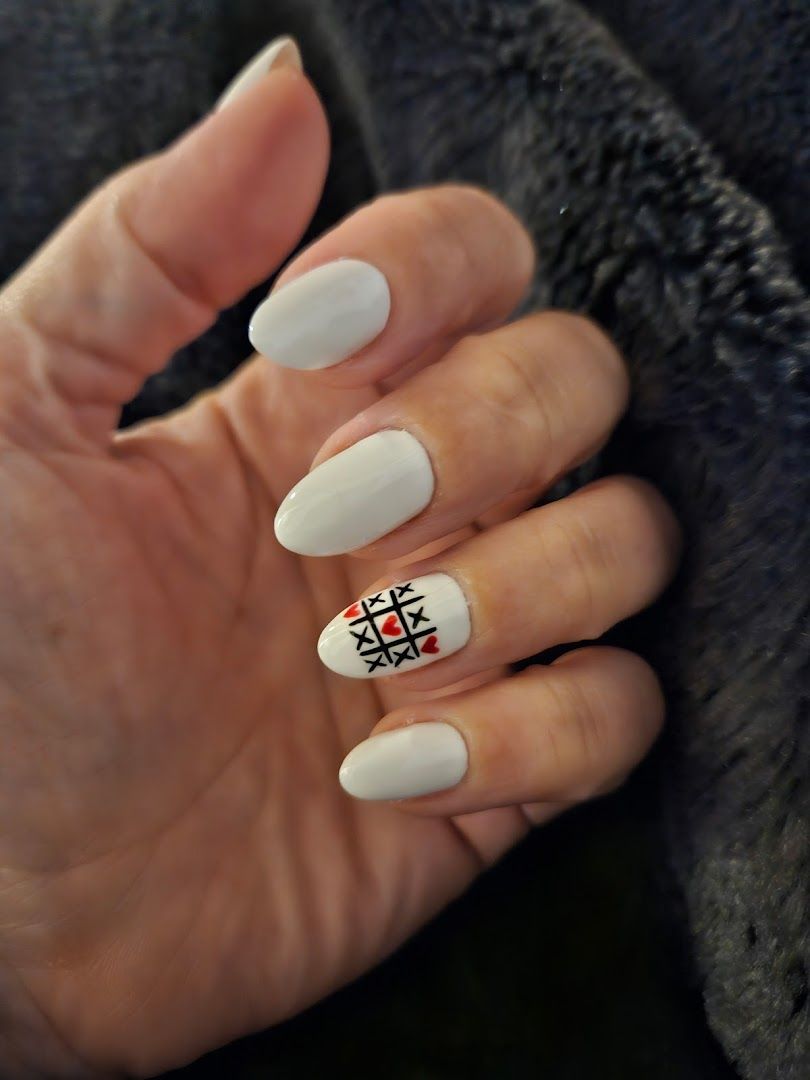 a woman's hand with white nails and a black and white cross on it