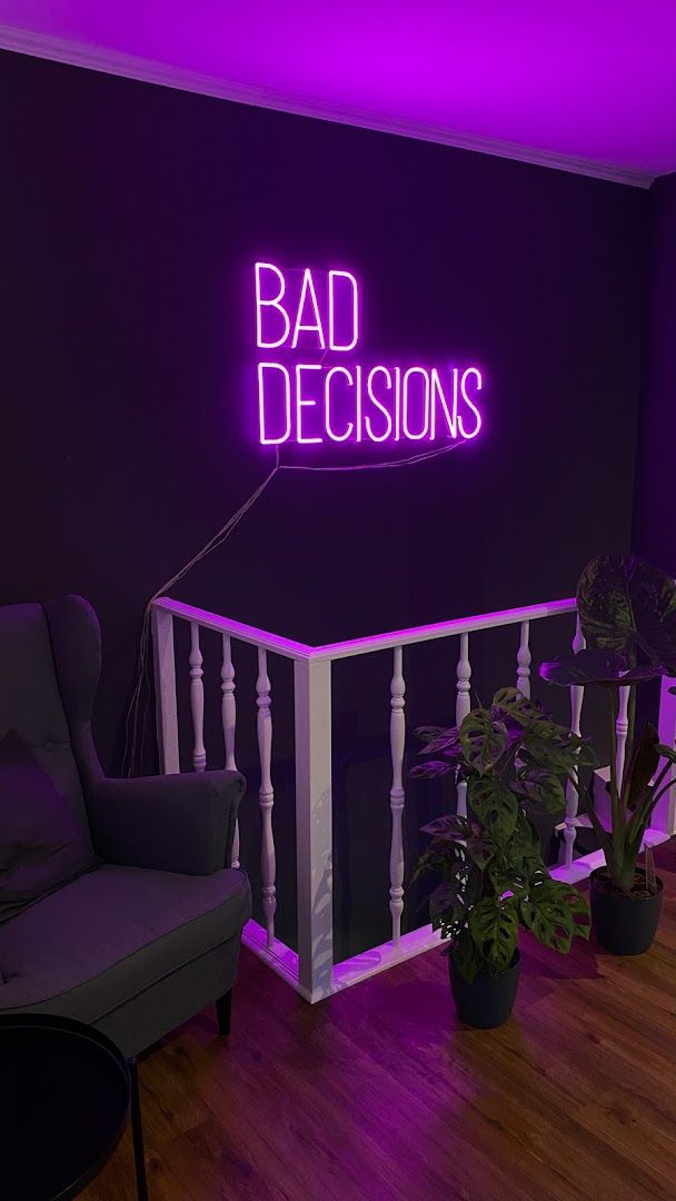 a purple neon sign that reads bad decisions