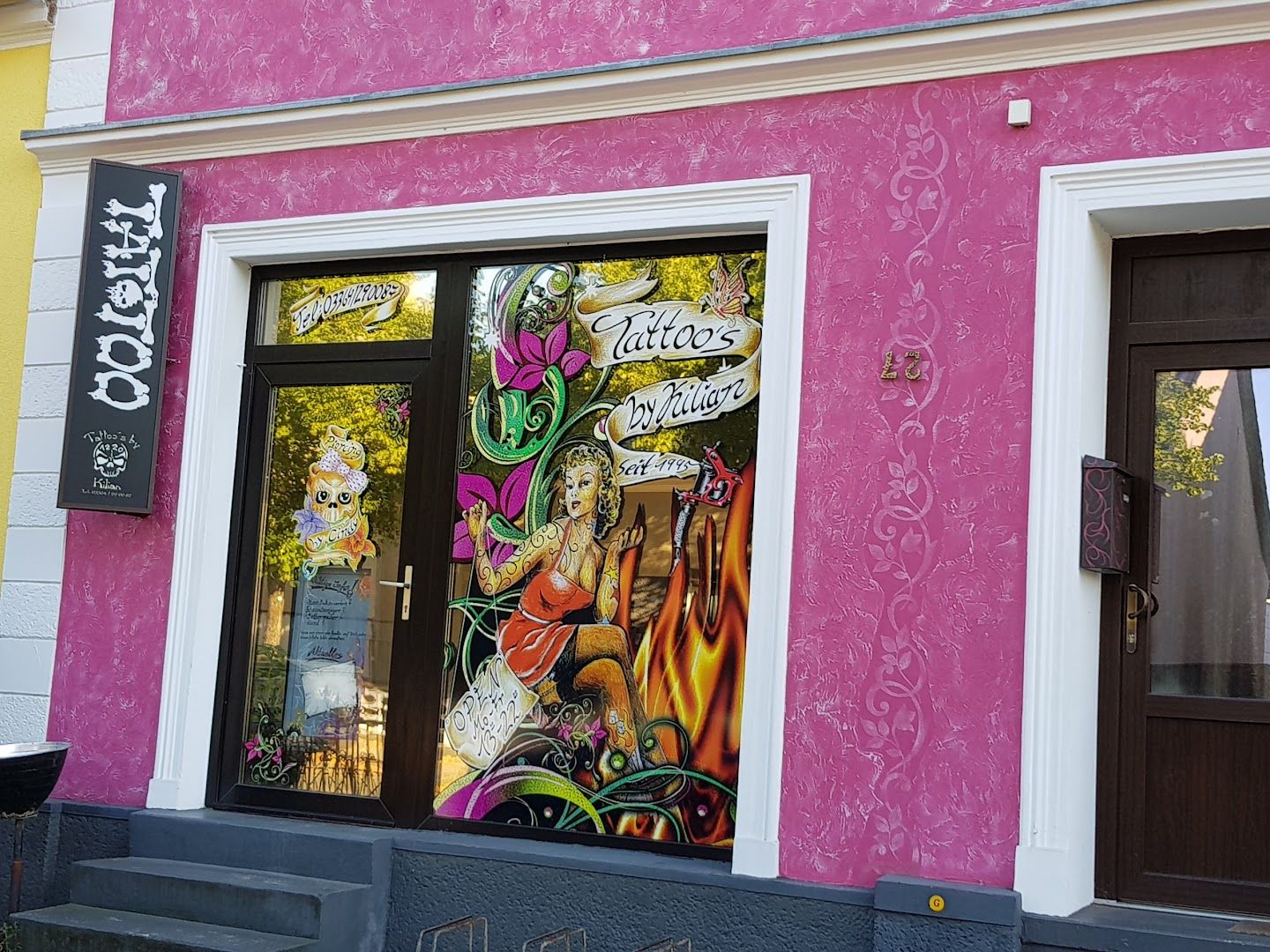 a pink building with a large window with a painting of a woman