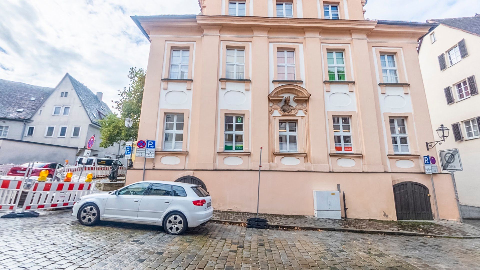 a white car parked in front of a pink building