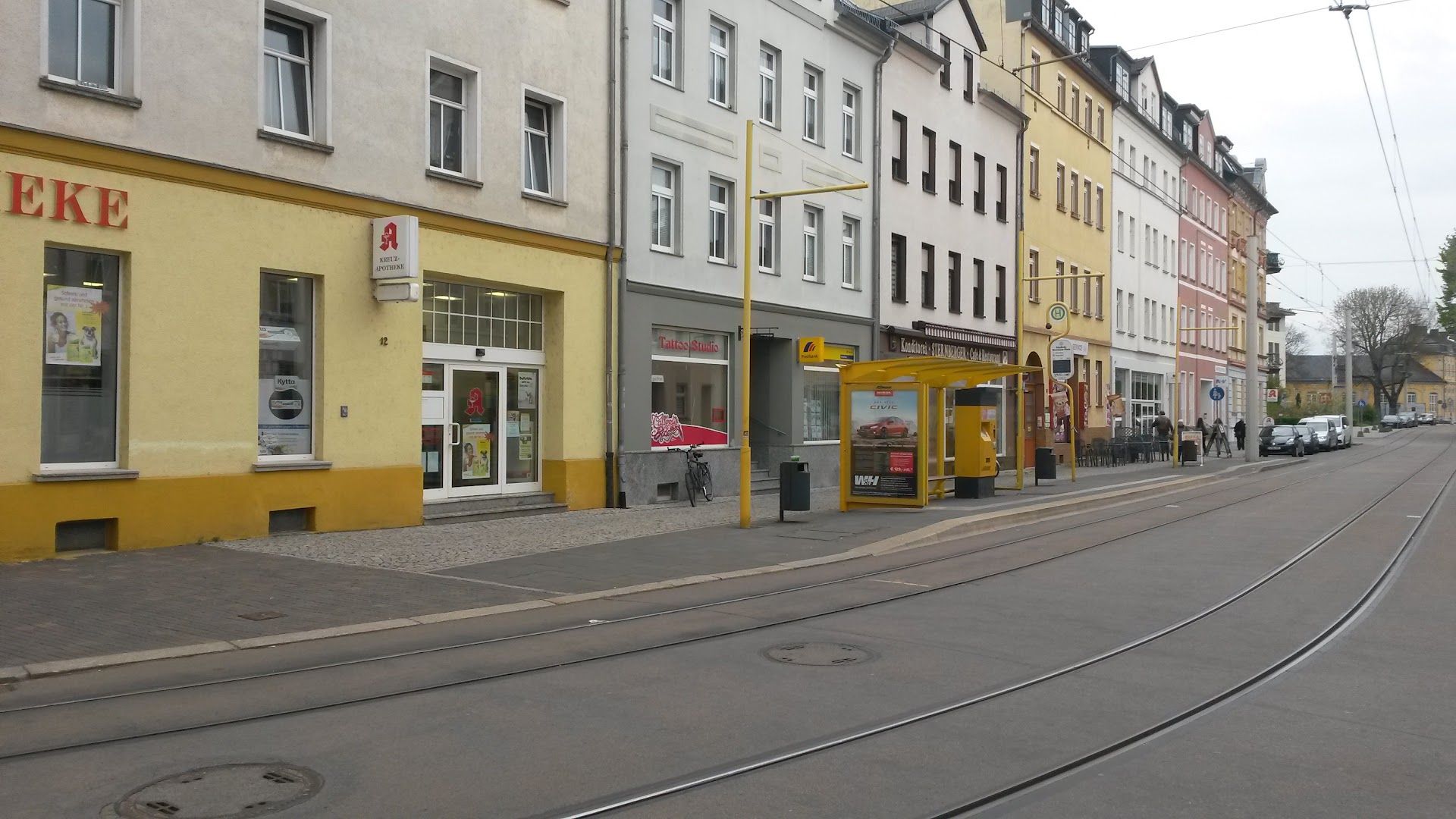 a street with a yellow building and a yellow tram car