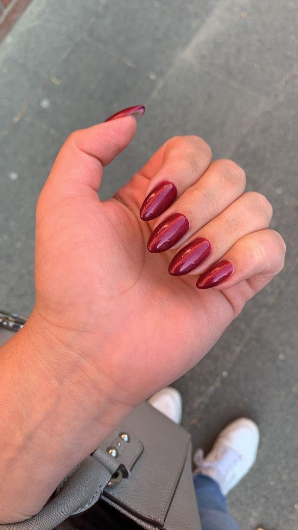 a woman's hand with a maroon mani and a black purse